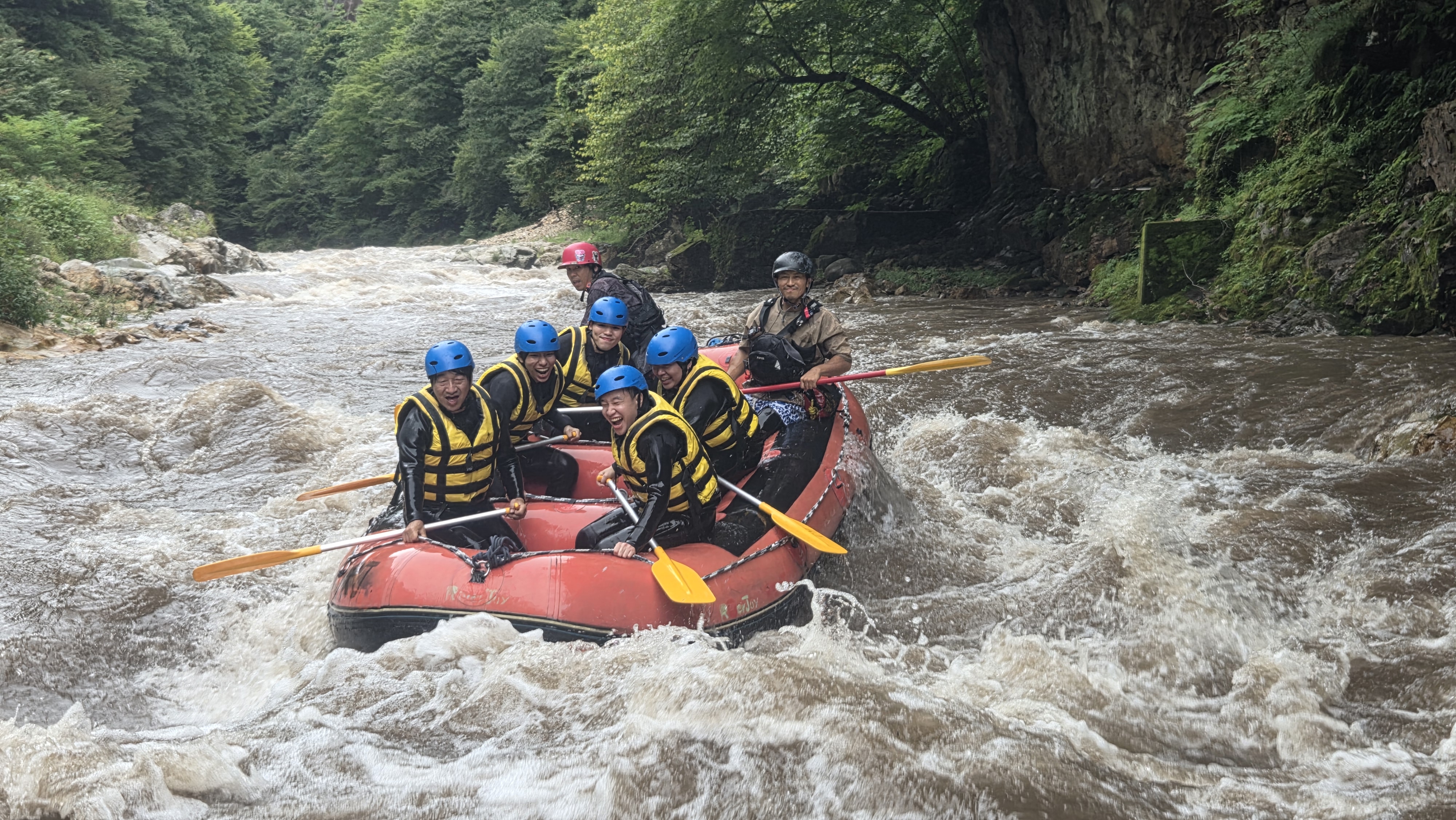 Rafting near Tokyo river rapid with guests wearing helmets and life jackets
